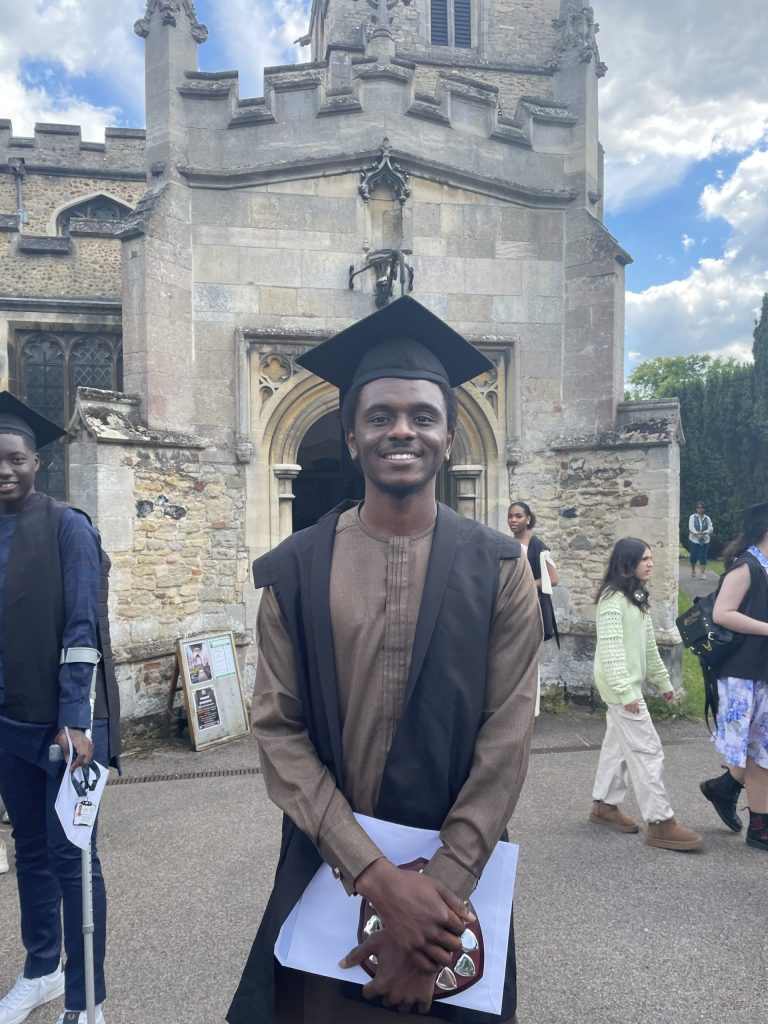 student in graduation gown, outside. student is valedictorian